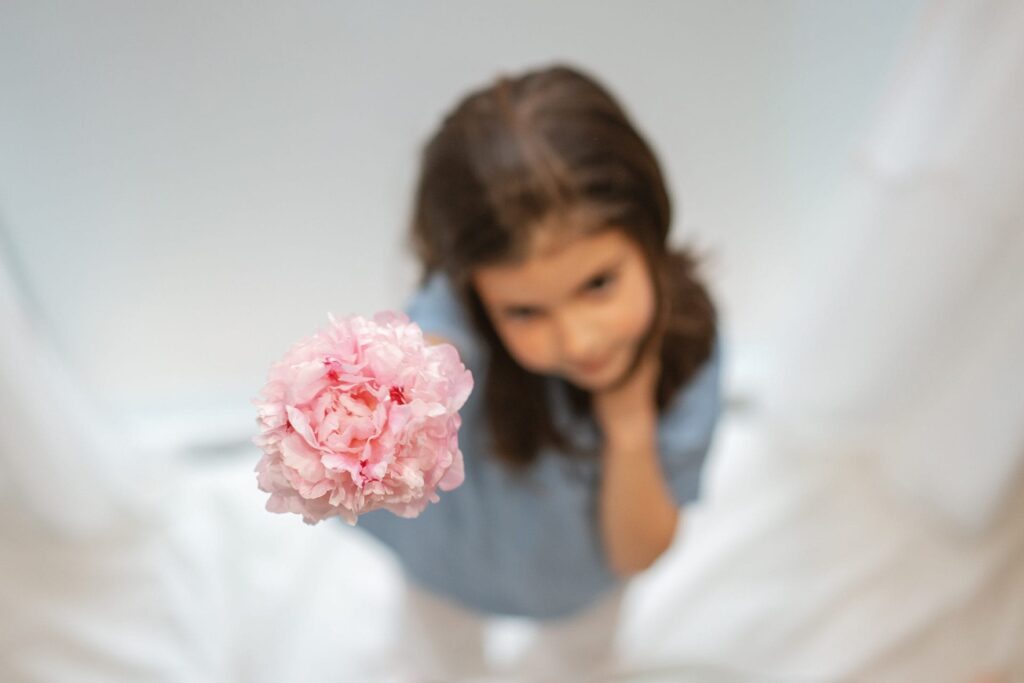 en pige, der holder en lyserød blomst