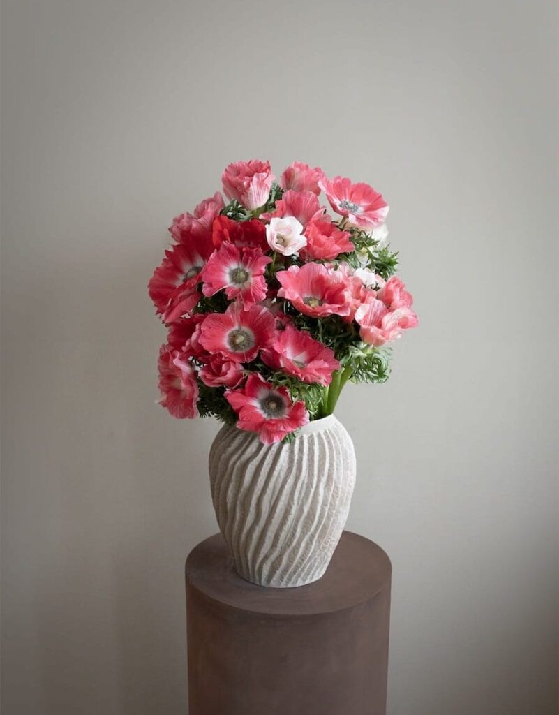 stor lyserød anemonebuket i skulpturel råhvid vase