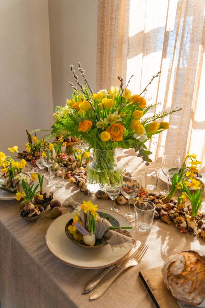 Påskebord med gul/orange buket, påskeliljer og pynt