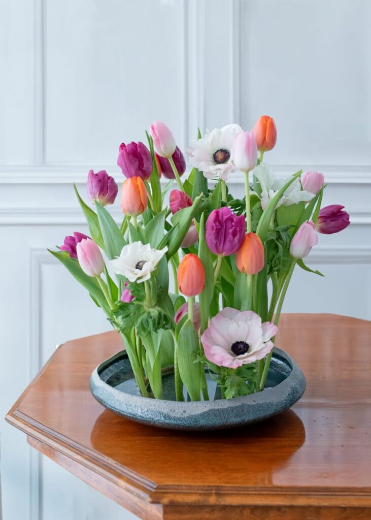 kunstnerisk buket i fad med farvestrålende tulipaner og anemoner