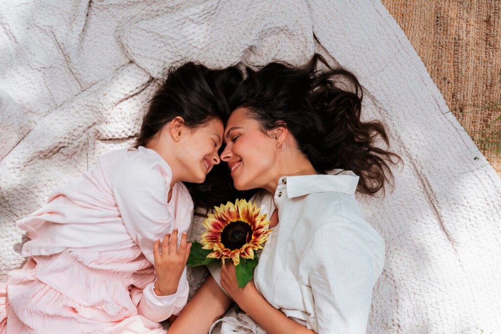 mor og datter med solsikke ligger på tæppe