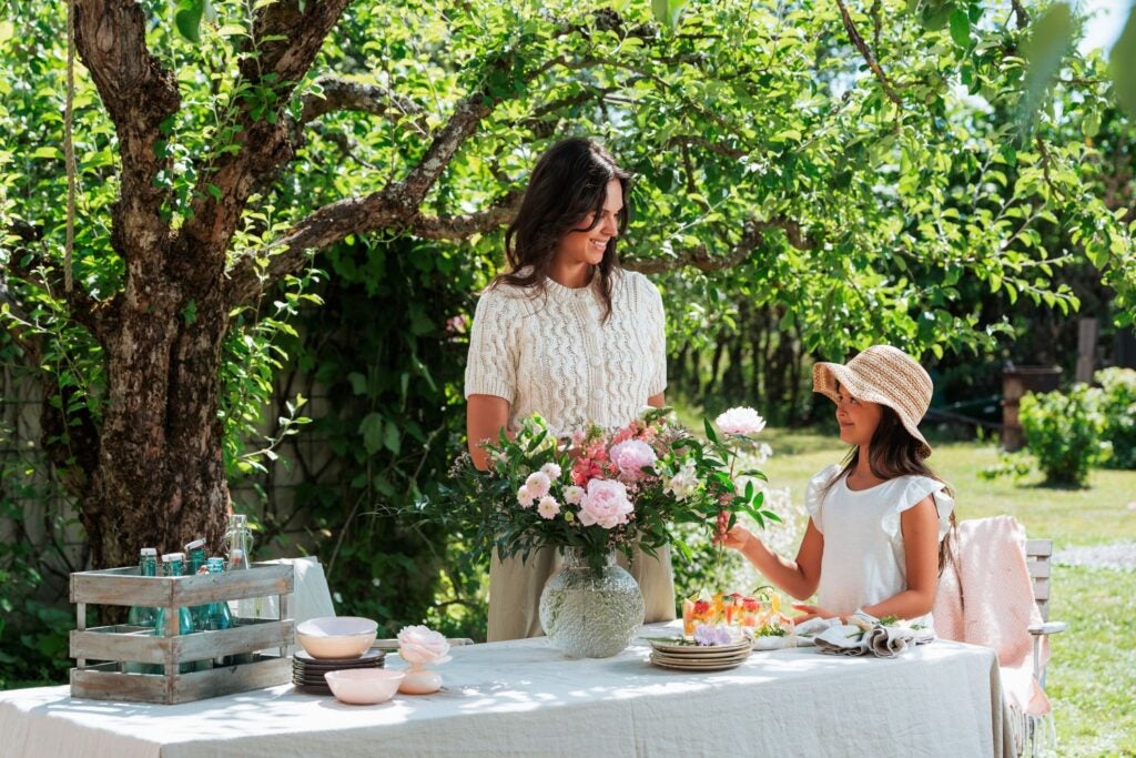smilende mor og datter med smukke blomster på bord
