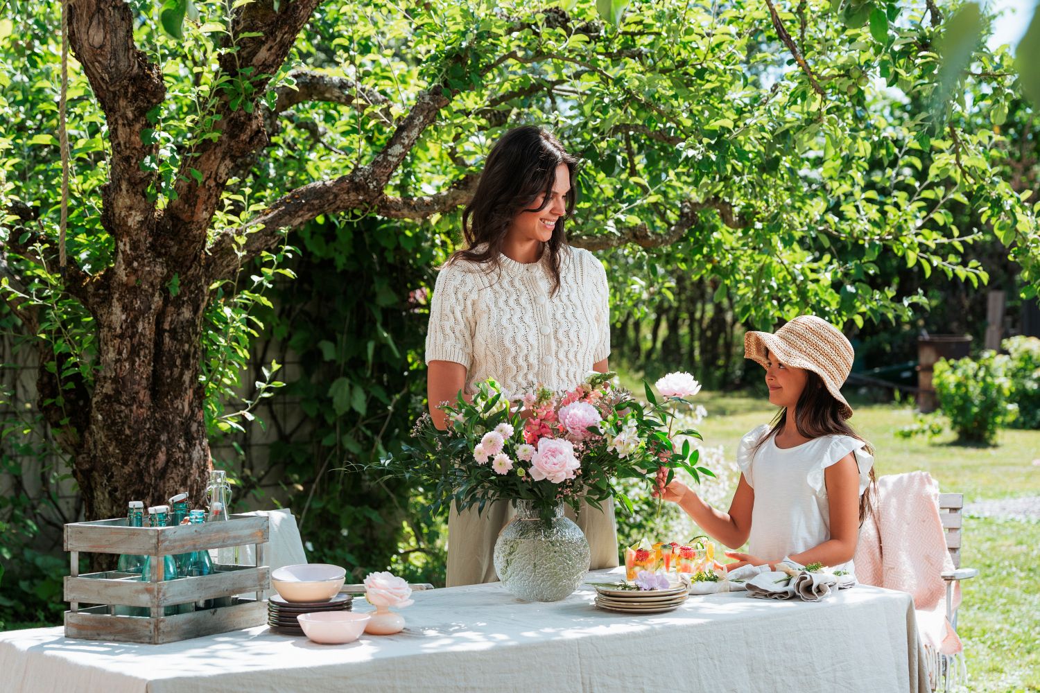 smilende mor og datter med smukke blomster på bord