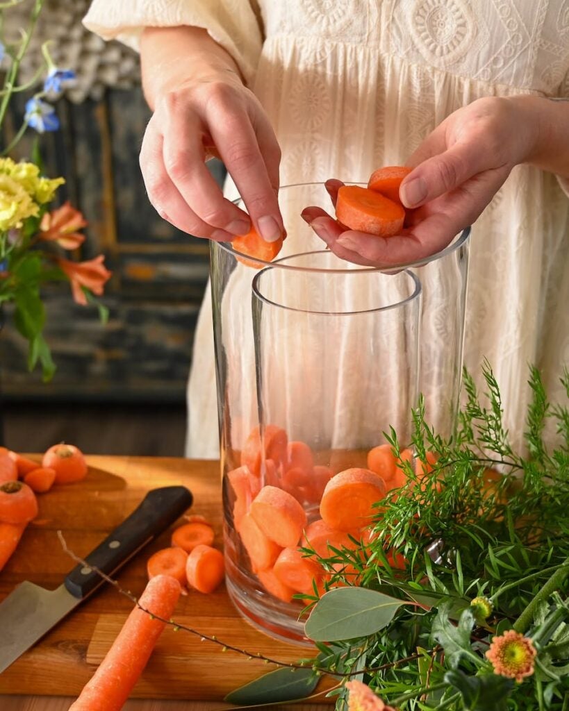 person laver påskeblomsterdekoration med gulerødder