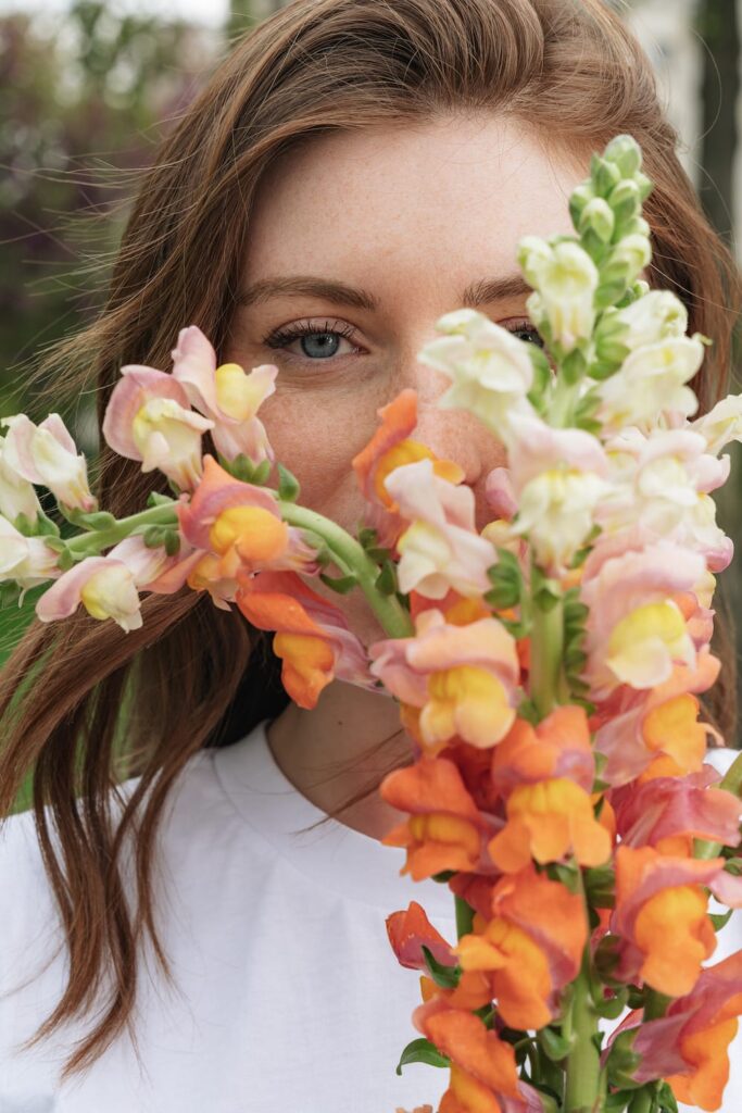 kvinde holder flot løvemund foran ansigtet