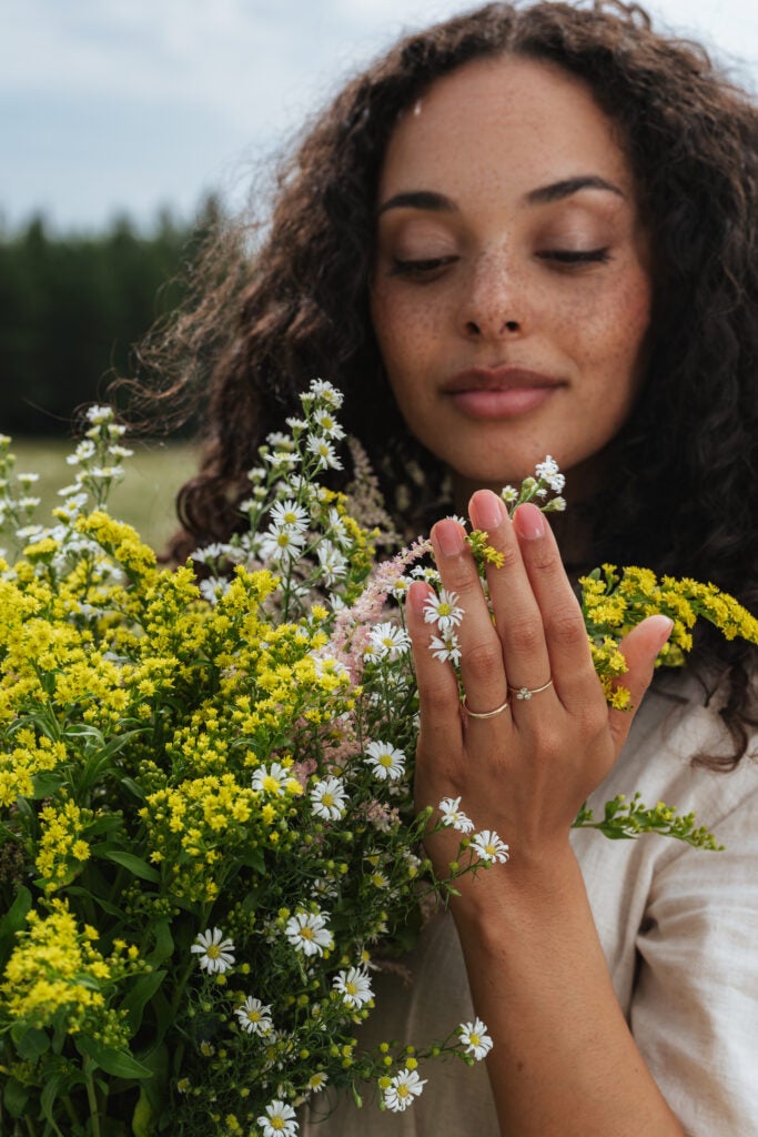 Kvinde holder hvide og gule naturblomster på mark