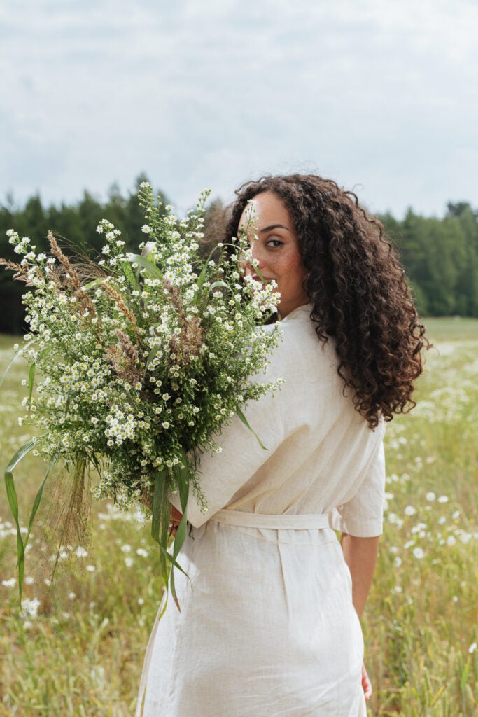 Kvinde holder hvide naturblomster på mark
