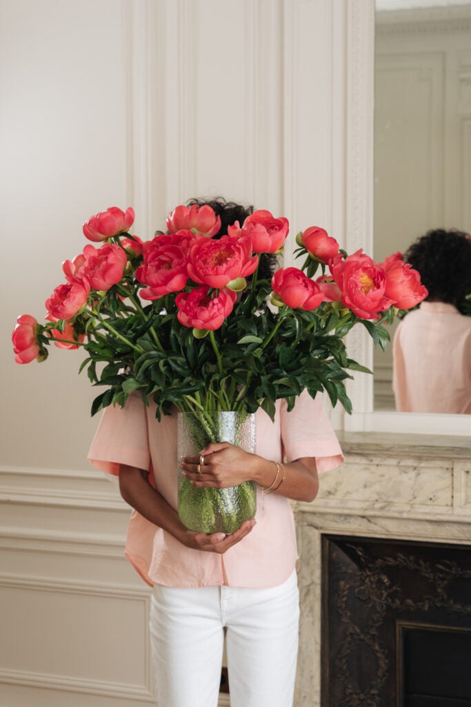 Kvinde holder stor og ekstravagant pæonbuket op foran sig