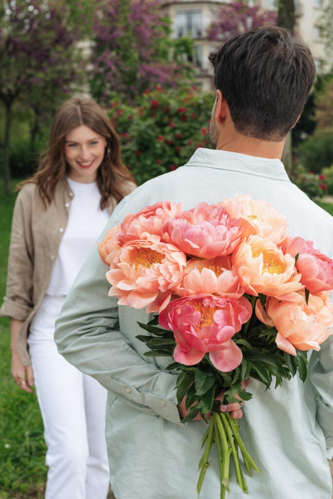 Mand holder pink pæoner bag ryg som overraskelse