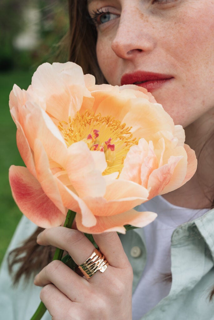 kvinde holder flot pæon foran ansigtet