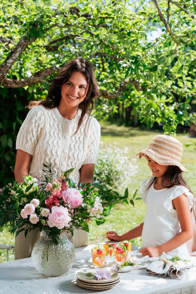 smilende mor og datter med smukke blomster på bord