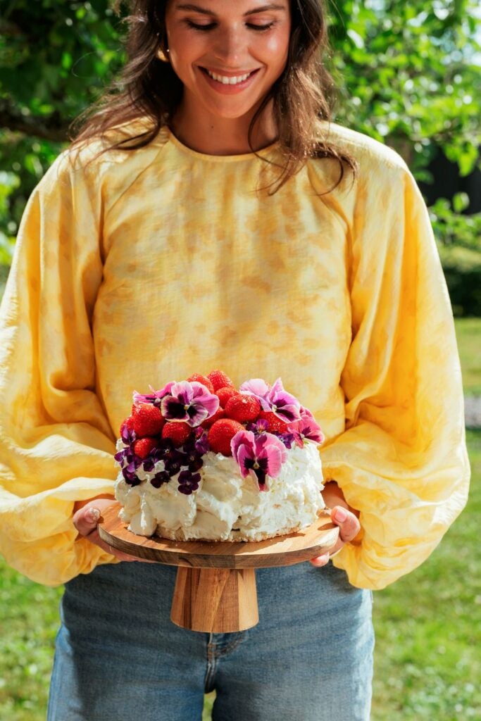 Kvinder holder flot og farverig kage med blomster og bær