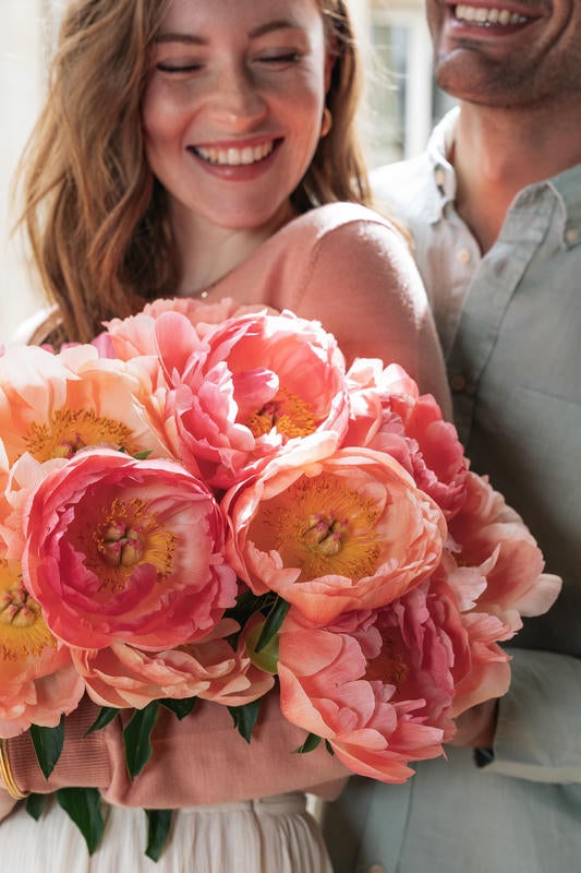 Kvinde holder en nuket af pinke pæoner