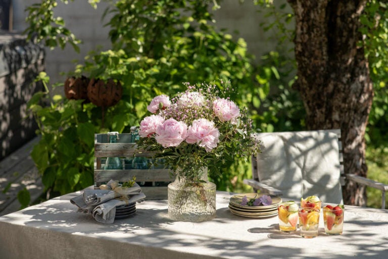 Lyserød pæonbuket på bord i have