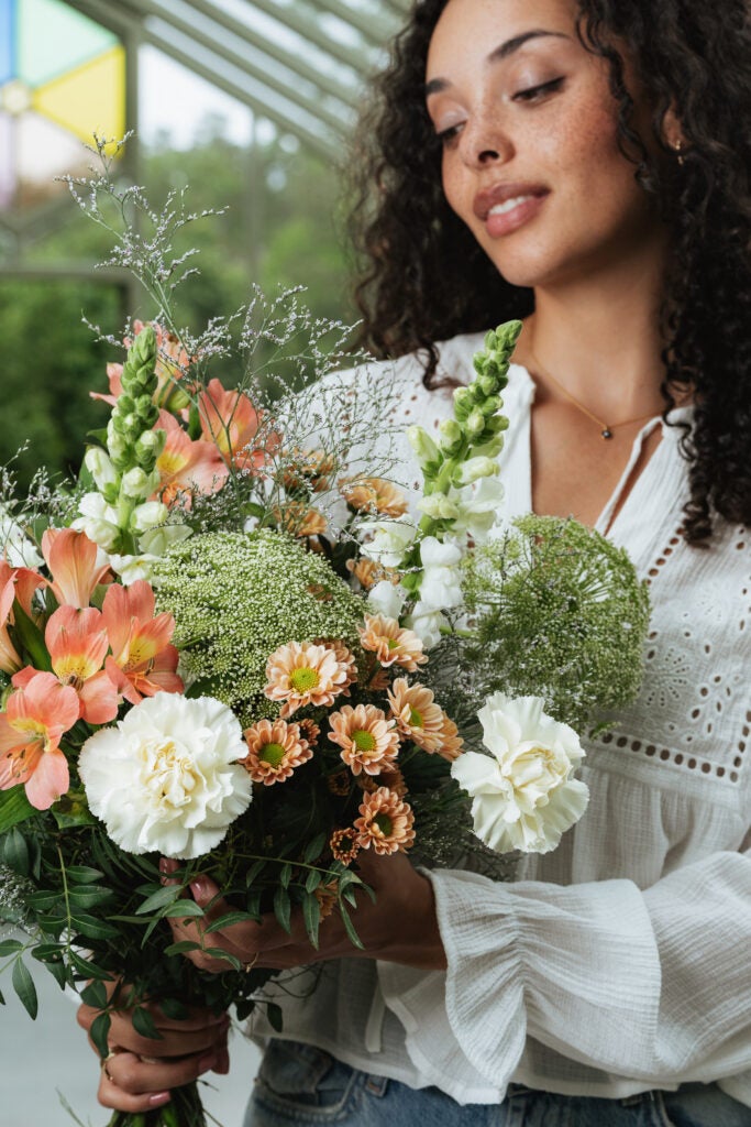 Kvinder holder fin buket i lyse nuancer fra interflora