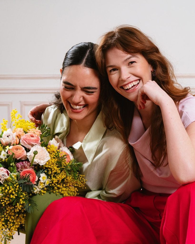 Smilende veninder med en smuk venskabsbuket fra Interflora