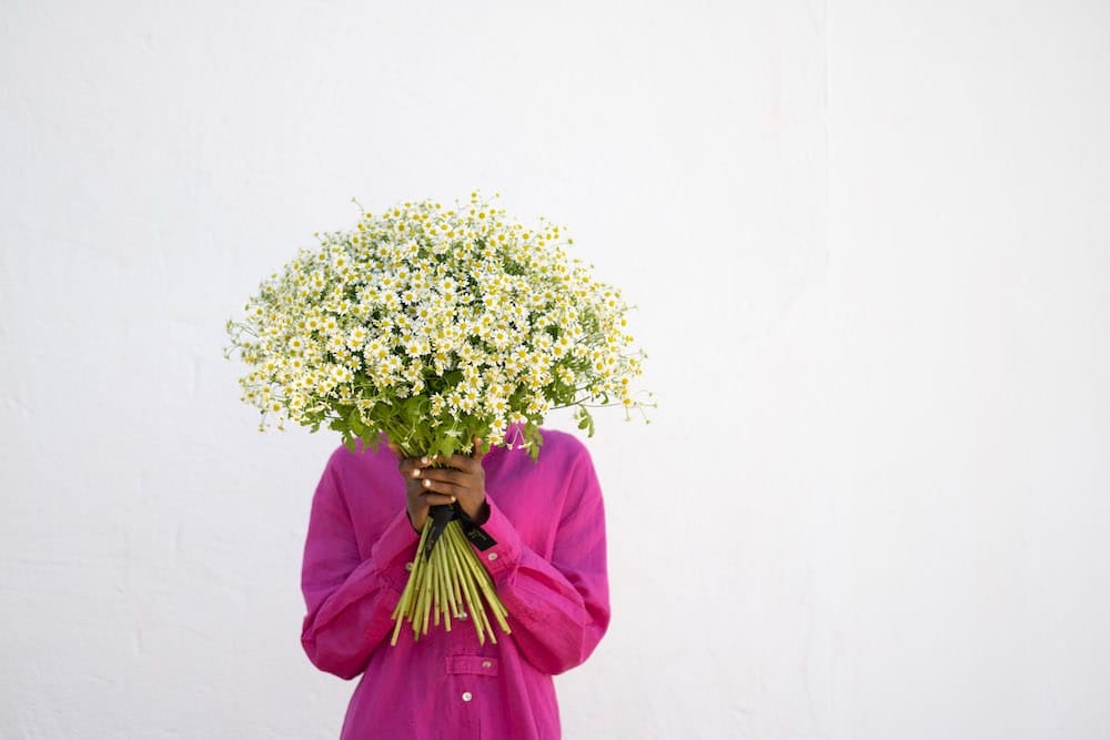 Dame holder stor buket af hvide blomster foran ansigtet