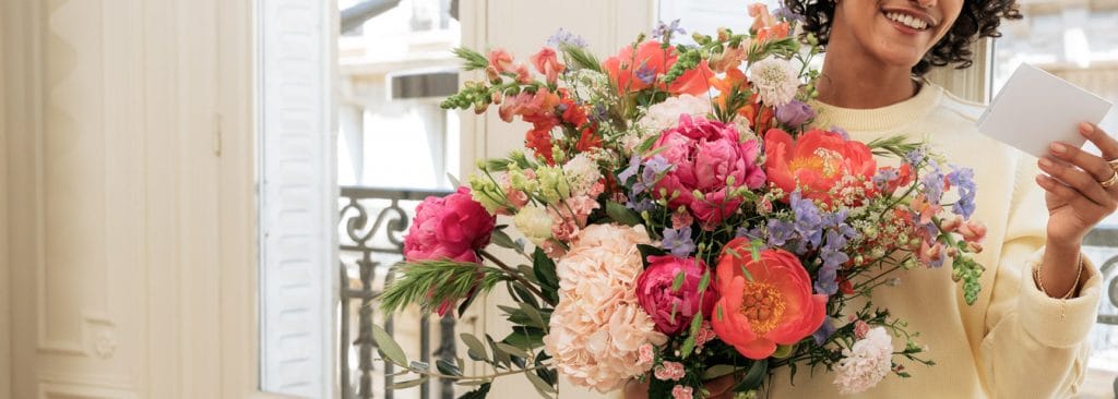 kvinde læser kort til overdådig buket i med lyserøde og orange blomster