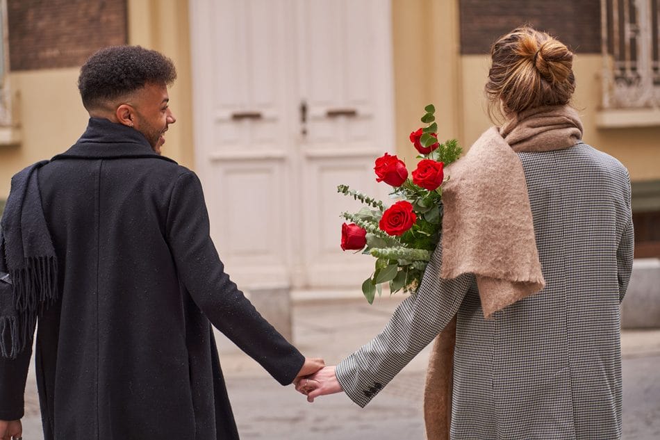 Par holder i hånden med røde roser Valentinsdag