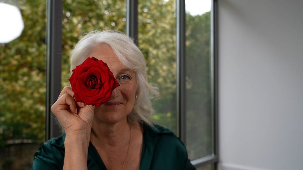 Bedstemor holder smuk rød rose foran øjet
