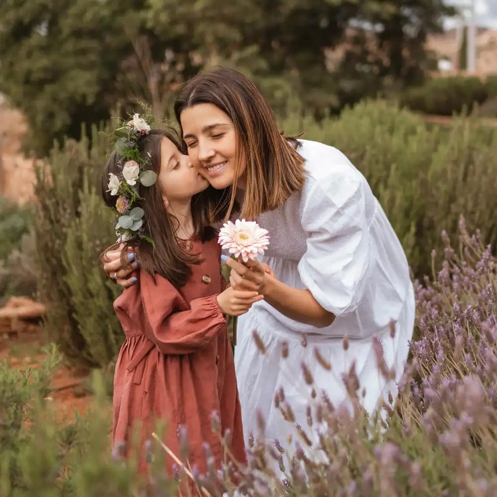 en pige kysser sin mor på en blomstermark