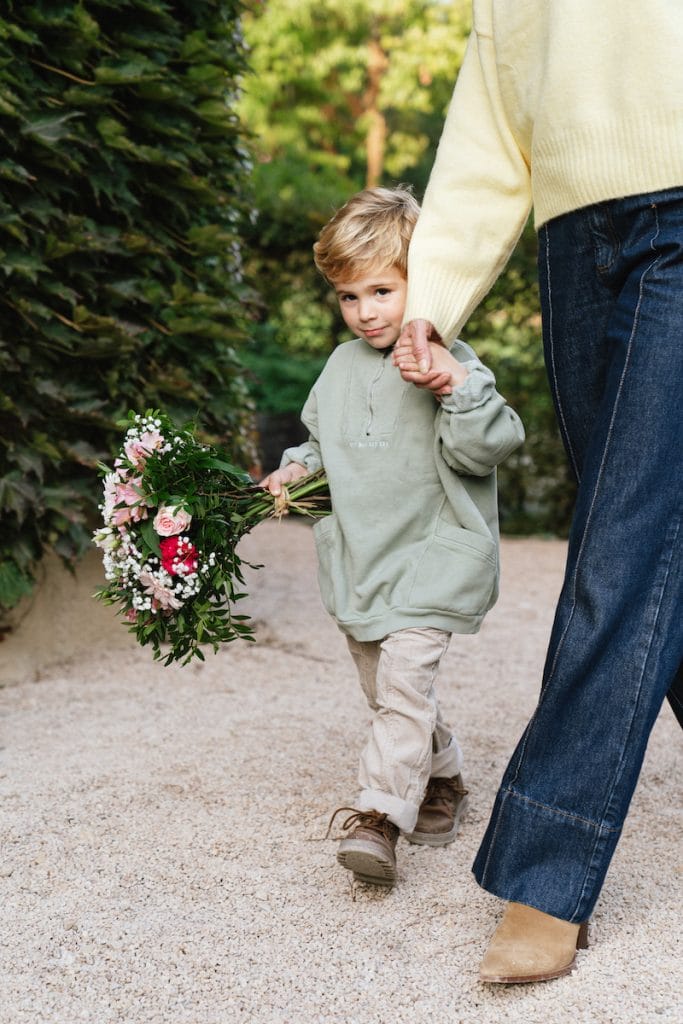 en lille dreng ledsaget af en voksen holder en buket blomster i hånden