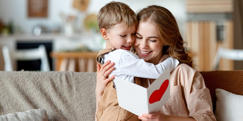 Mom happily reading card from son