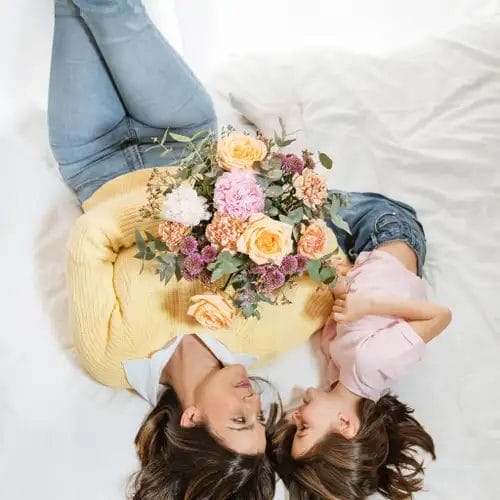 en mor og datter i sengen med en buket blomster