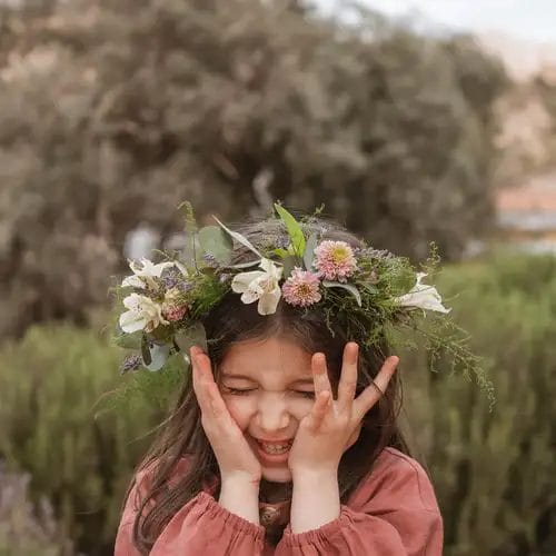 en lille pige med en krone af blomster på hovedet