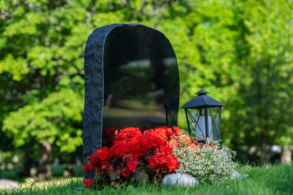 gravsten med røde blomster og lanterne