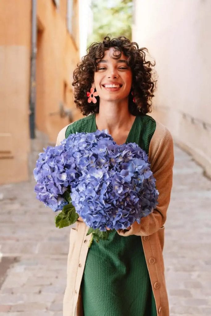 En ung kvinde holder blå hortensiablomster