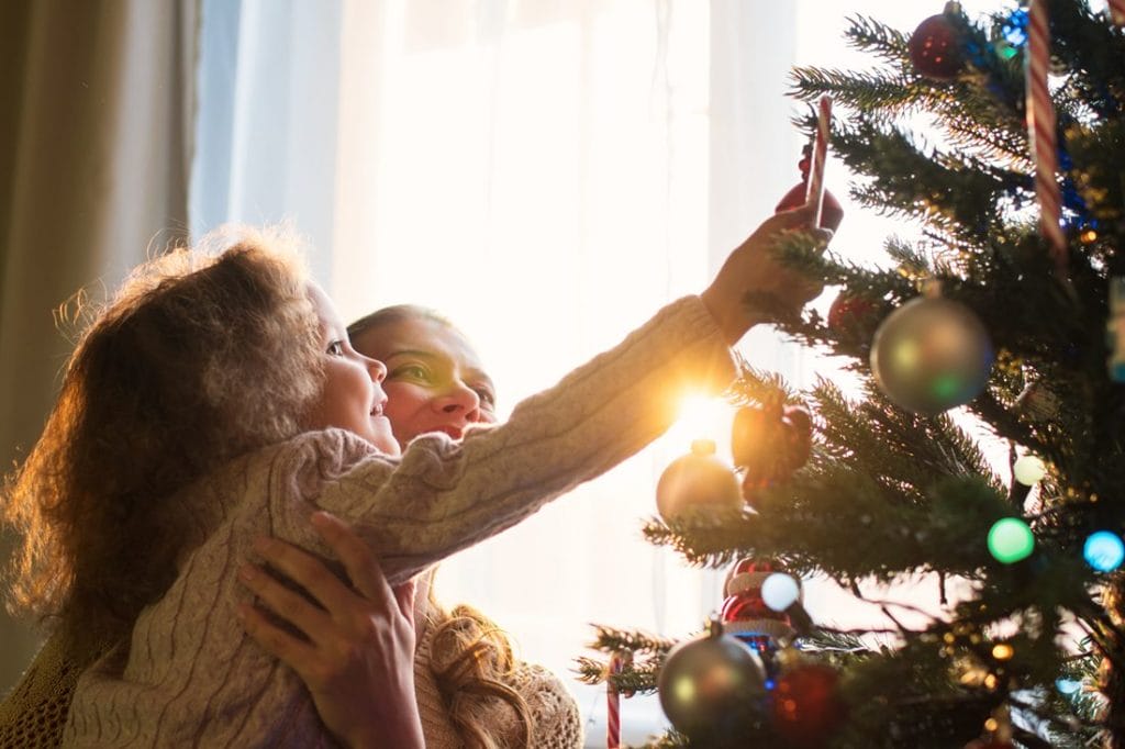 En pige og hendes mor pynter juletræet