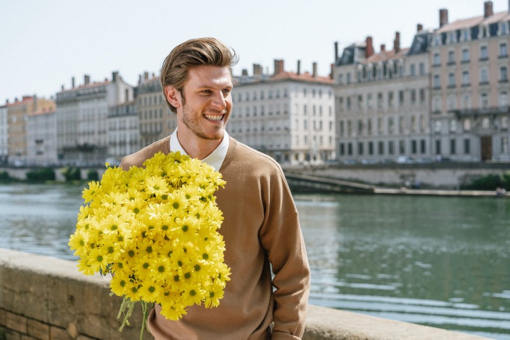 en mand med en stor buket gule blomster i hånden