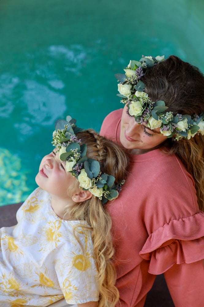 mor og datter sidder sammen med blomsterkrans på hovedet