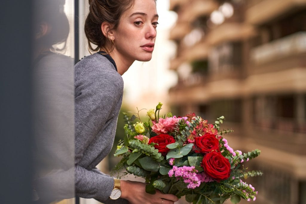 En ung kvinde kigger ud i det fjerne med en smuk buket blomster i hånden.